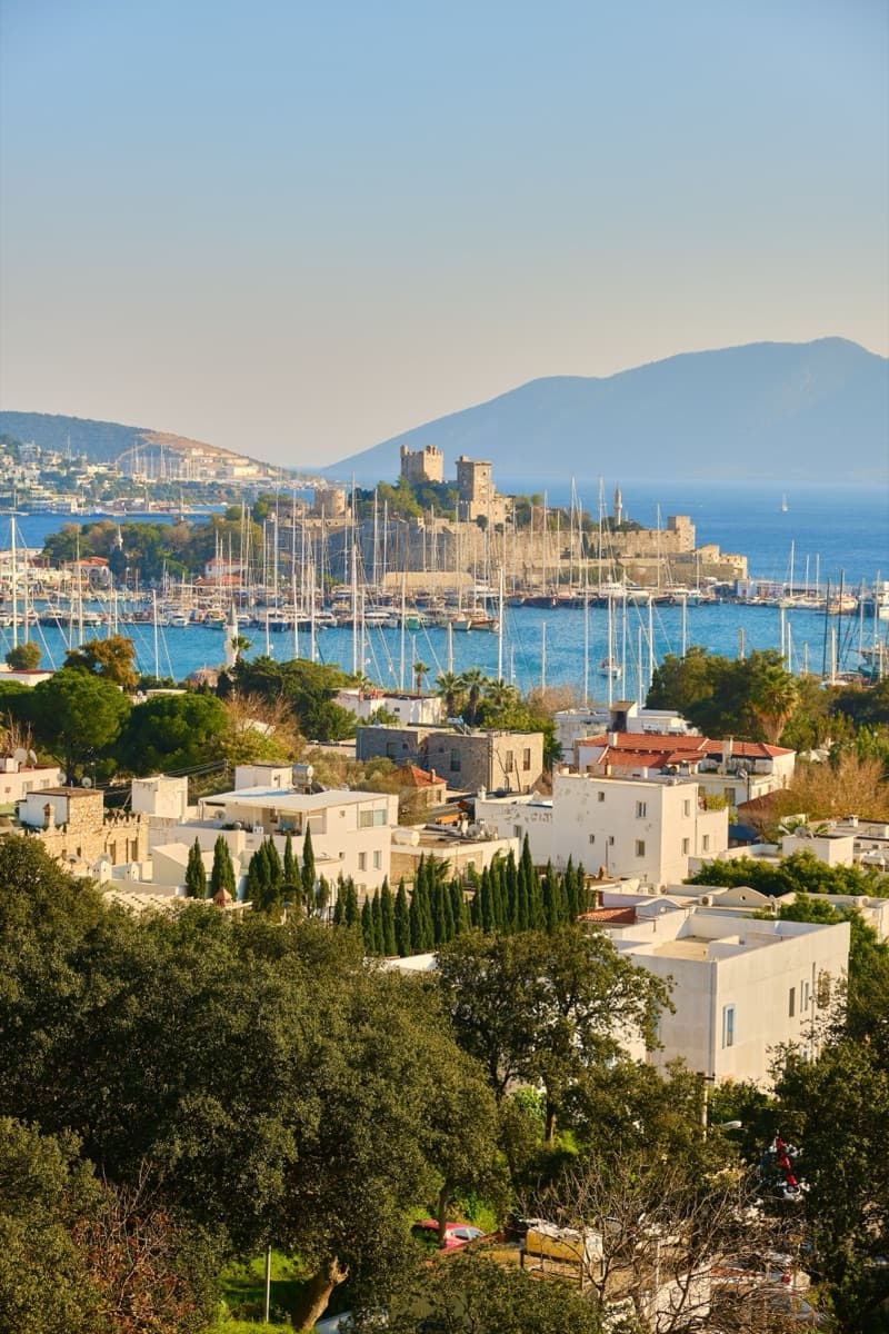 Bodrum Castle across a harbour full of sailing masts, white flat-roofed houses in the foreground