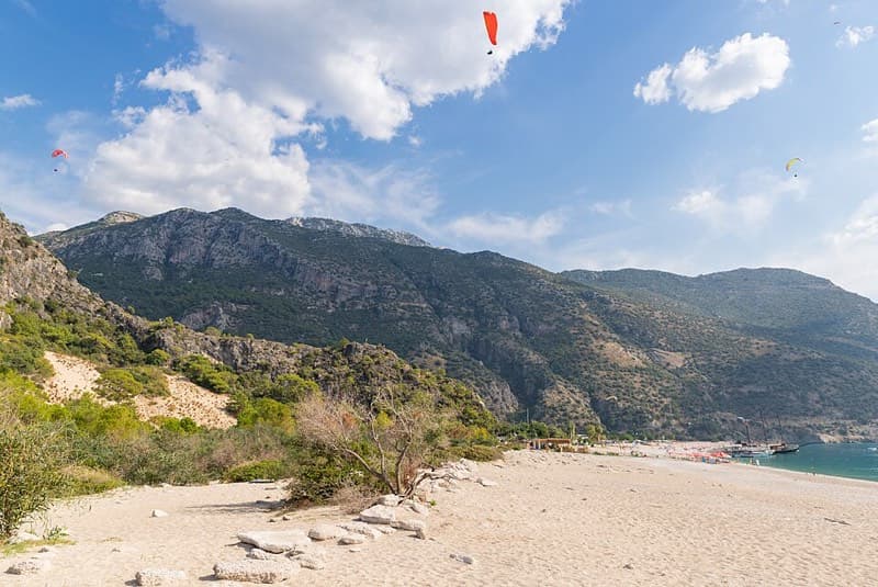 A paraglider drifting over the turquoise Blue Lagoon at Ölüdeniz